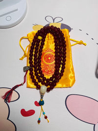 Red Tibetan prayer beads mala with 108 beads, decorated with turquoise and white jade guru bead, placed on golden silk pouch