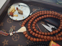 Tibetan square bodhi seed prayer beads with ivory-colored guru bead and multicolor tassel, meditation mala on decorative surface