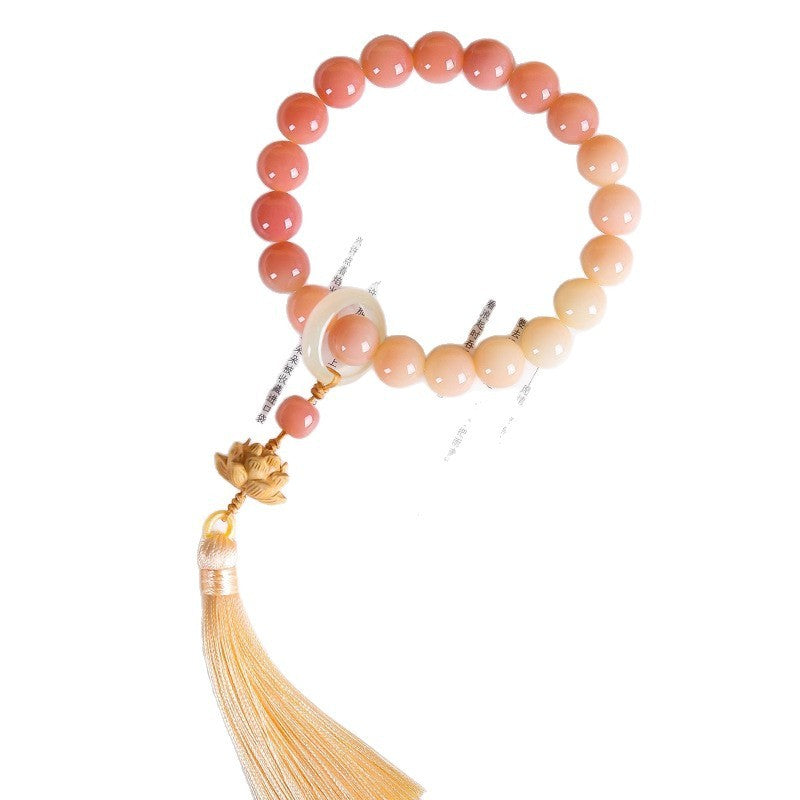 Peach-gradient bead loop with resin ring and boxwood lotus; tassel tips extend beyond the lower edge.