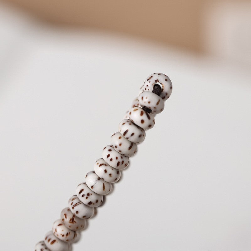 Close-up of pale speckled star-and-moon bodhi beads and their perforations