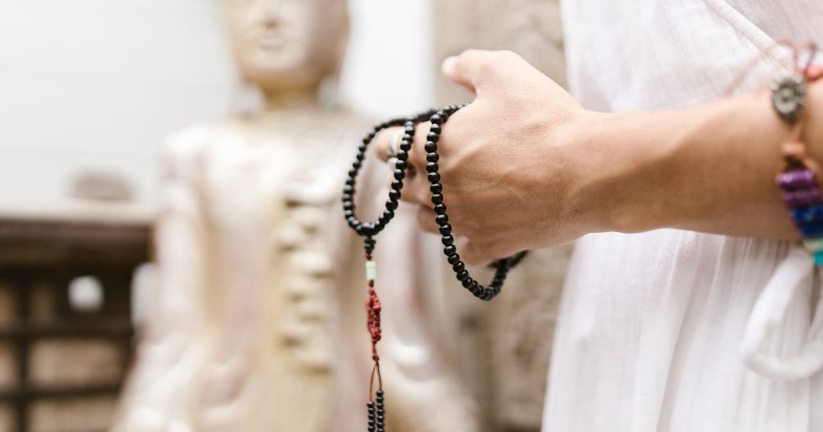 Tibetan Buddhist mala bracelet held with Buddha statue — Buddha bracelet meaning and benefits