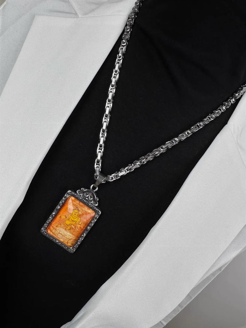 Tibetan Buddhist amulet necklace with golden deity carving, silver frame pendant shown from different angle on black shirt and white jacket