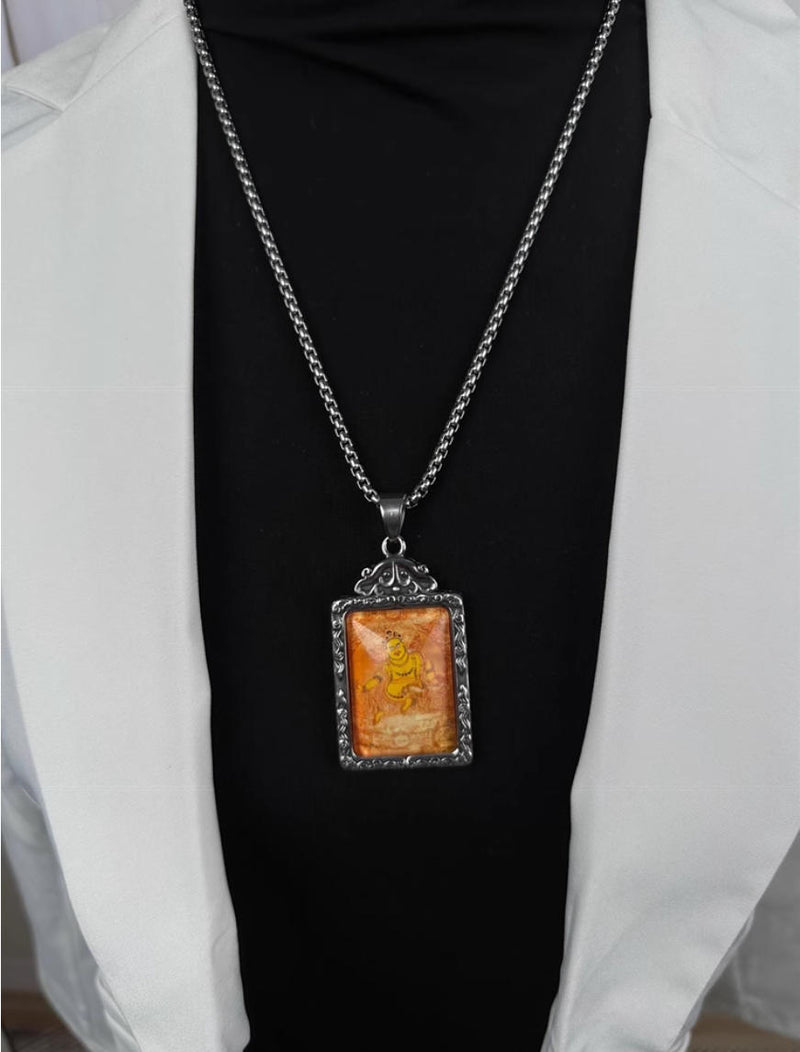 Tibetan Buddhist amulet pendant with golden deity carving on silver frame, worn as necklace for spiritual protection