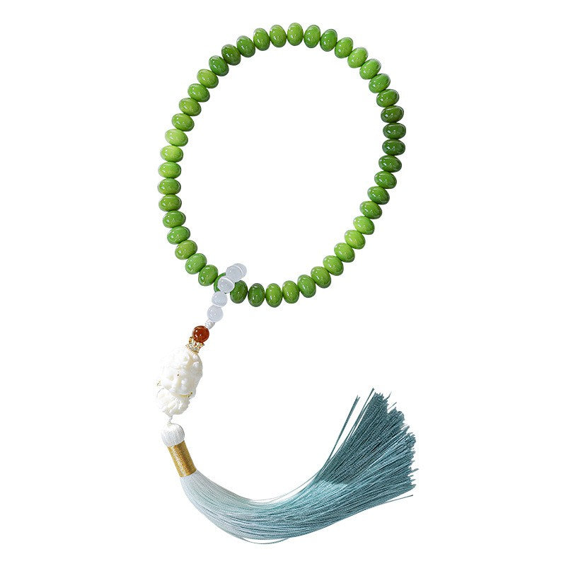 Complete green bodhi-root handheld strand with pale figurine, red accent bead and blue-green tassel on white.