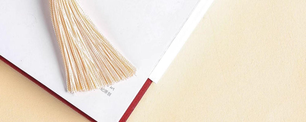 Close view of the pale tassel ends resting on a book.